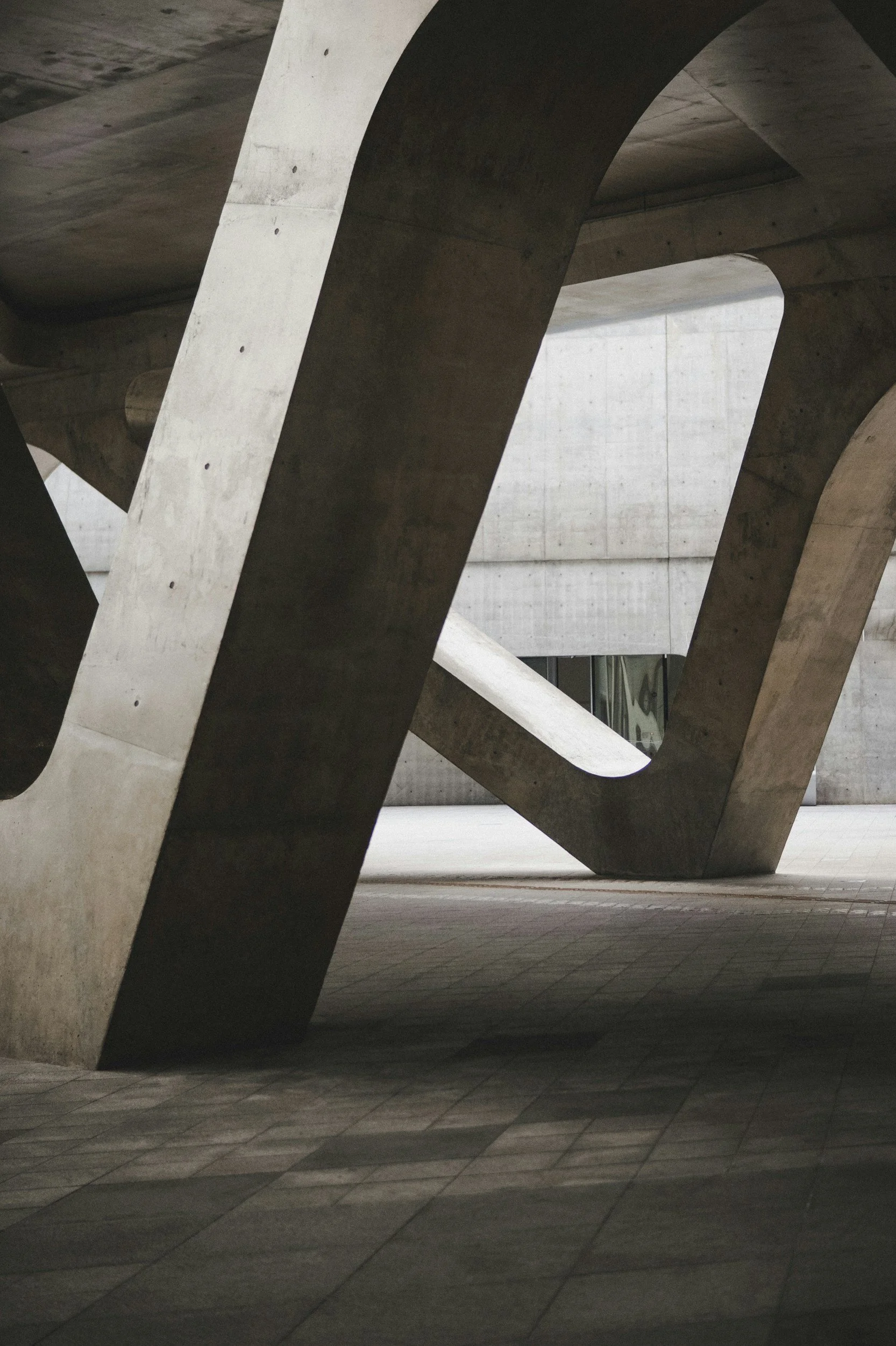 Close-up of concrete architectural structures with large angular supports and open spaces, possibly part of a modern building or monument.