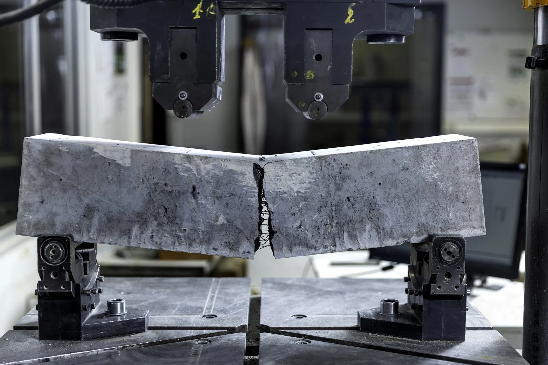 A quarry stone block being cut by a wire saw with multiple motors and pulleys in an industrial setting.