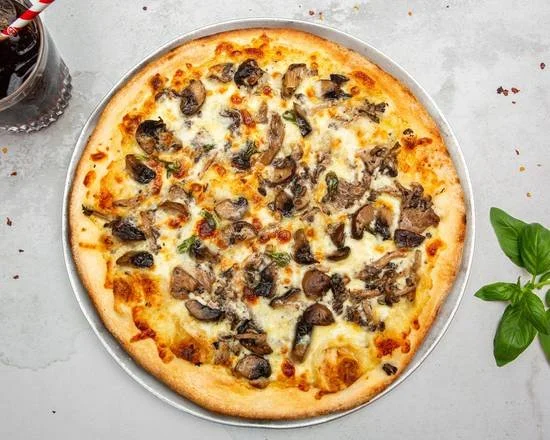 Cheese and mushroom pizza on a silver tray with a bottle of soda and a sprig of basil on the side.