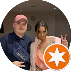 Two young women taking a selfie, one with a pink cap and blue adidas jacket, the other making a peace sign, with an orange star logo in the bottom right corner.