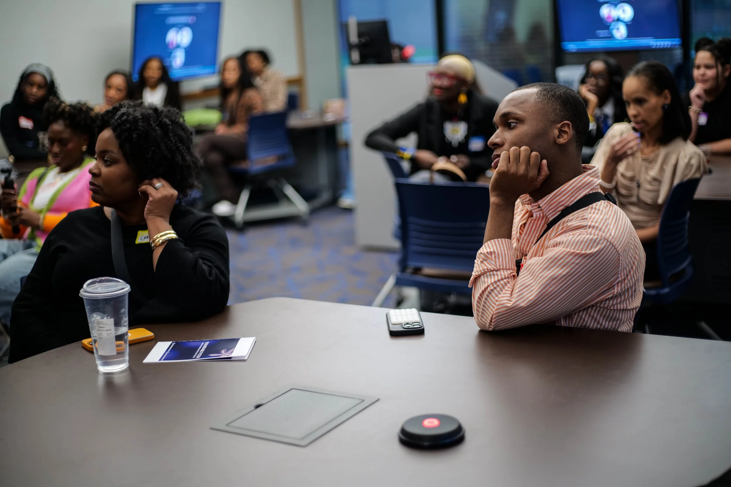 People sitting at a conference table, listening attentively to a presentation in a modern conference room.