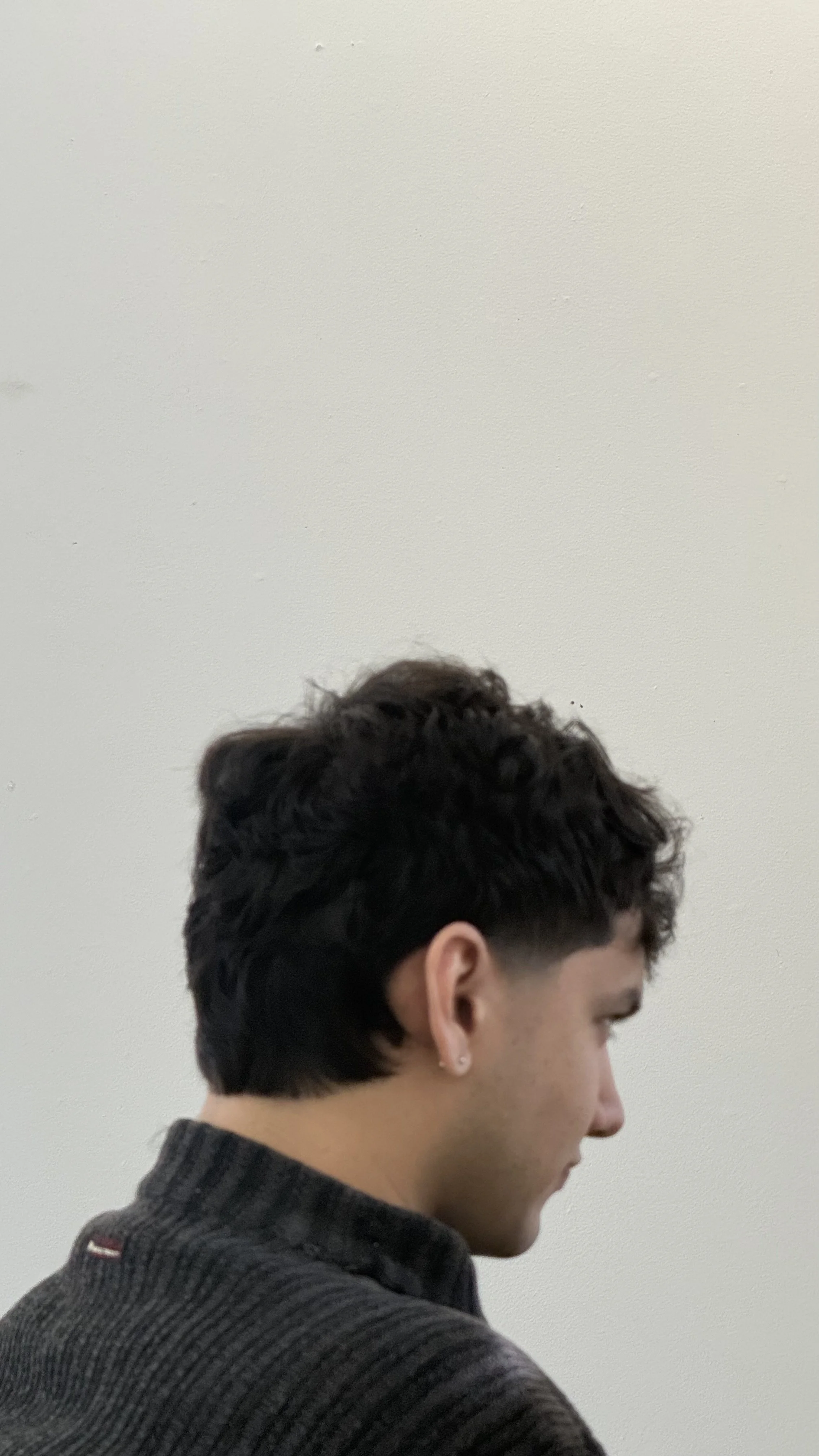 Profil d'une femme avec cheveux courts en arrière-plan d'un mur blanc.