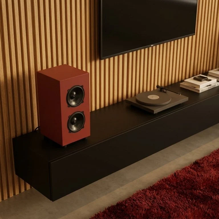 Sistema audio con altoparlante rosso, giradischi con vinile, e riviste su mobile nero di fronte a parete di pannelli di legno verticali, e parte di tappeto rosso.