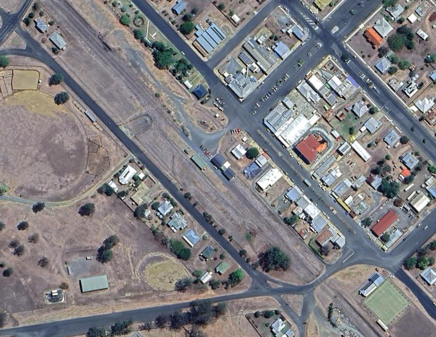 Aerial view of a train track running through an urban area with residential houses and streets adjacent to it.