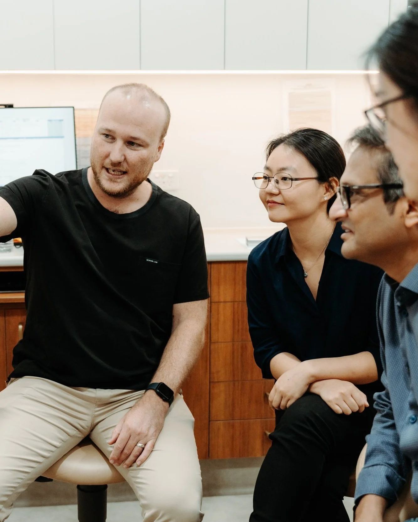 A diverse group of professionals engaged in a discussion in an office setting, with one person gesturing while others attentively listen.
