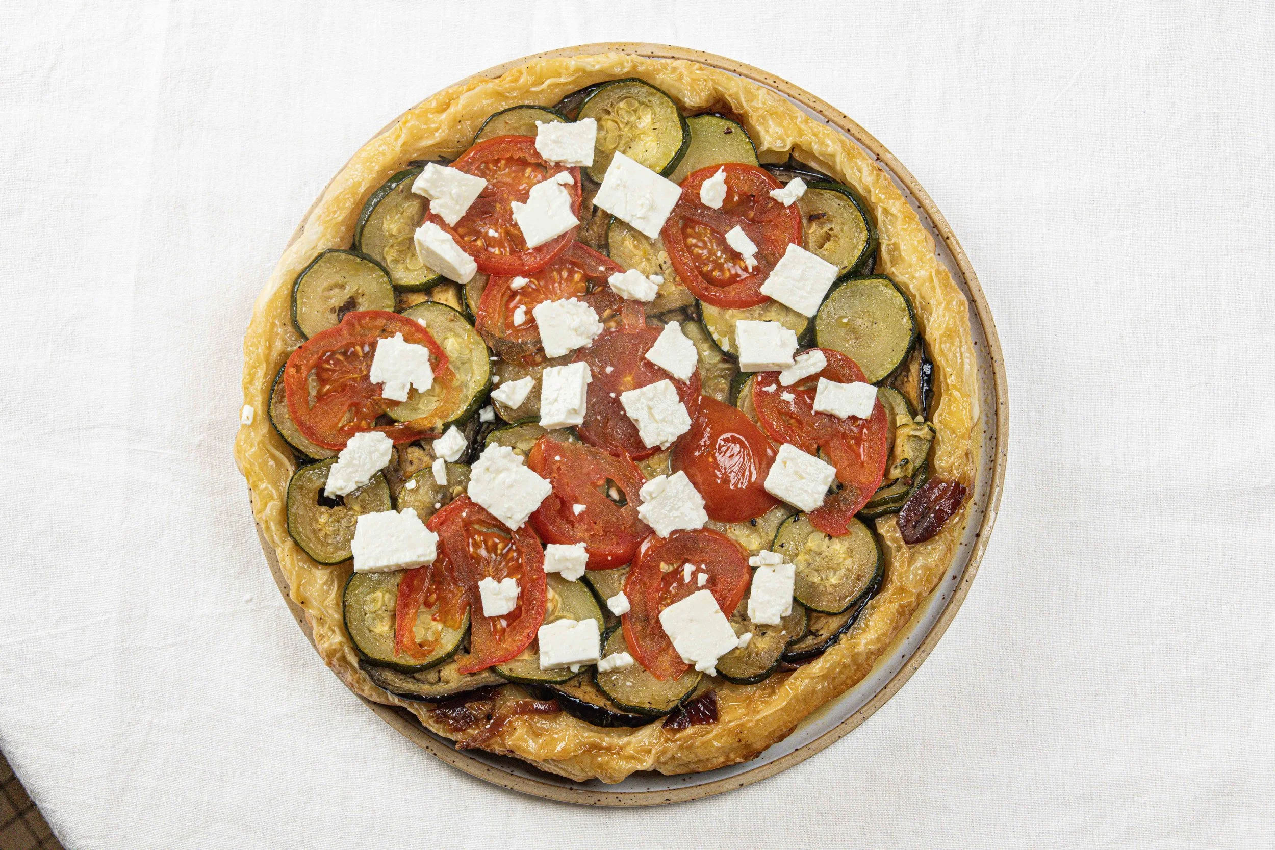 Une tarte aux légumes composée de courgettes, tomates, et feta. Par le photographe culinaire Yves Daniel. 