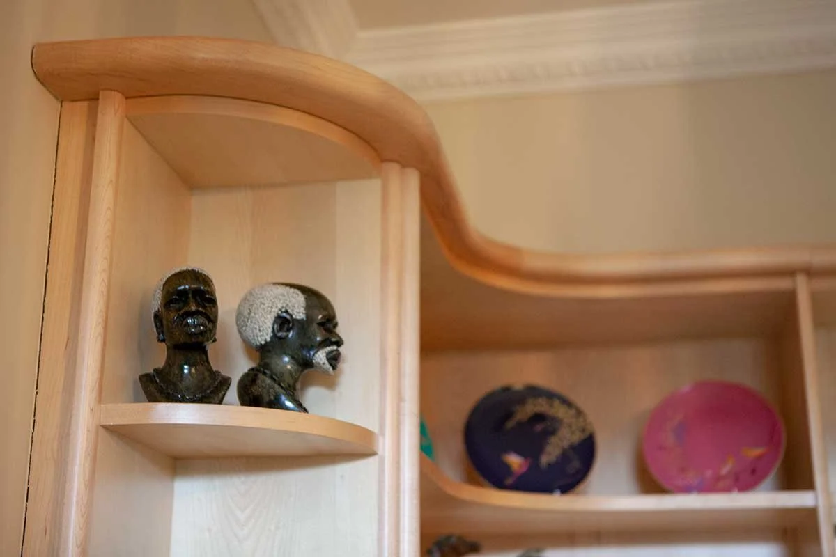 Decorative black bust sculptures of African figures on a wooden curved shelf.