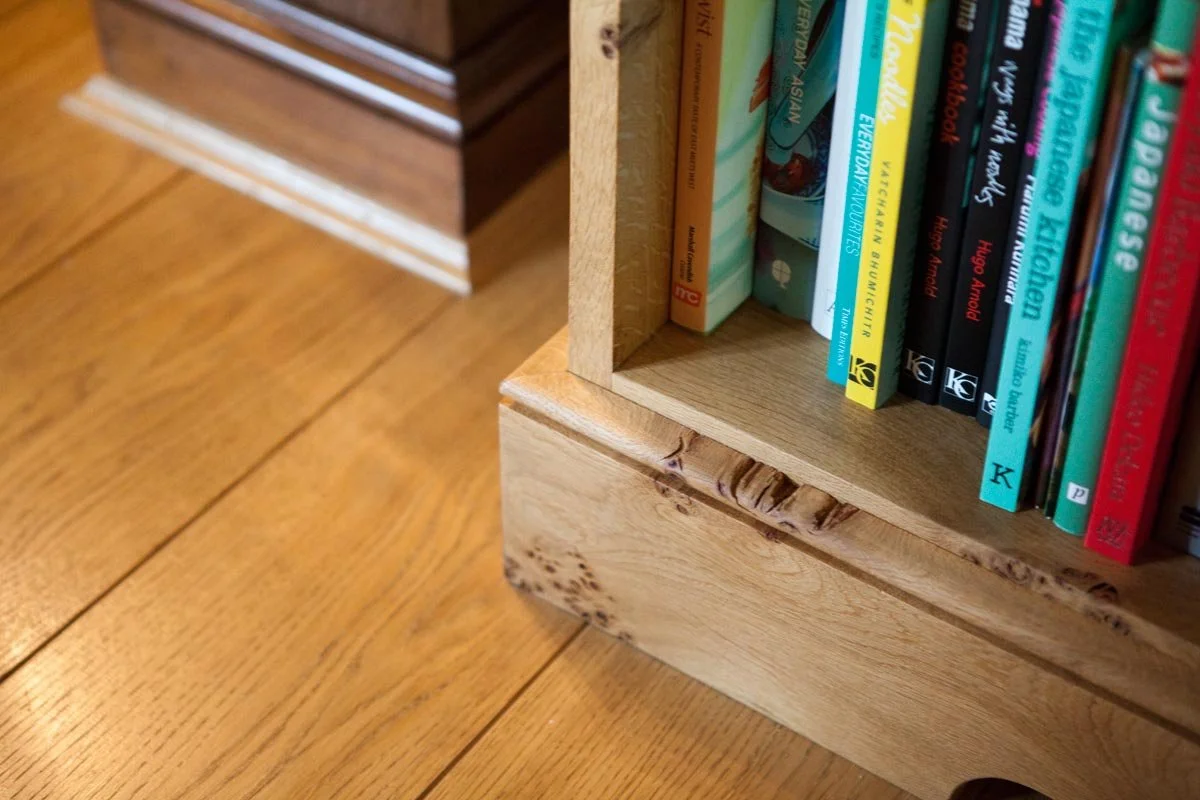Part of a wooden bookshelf with books on a wooden floor.