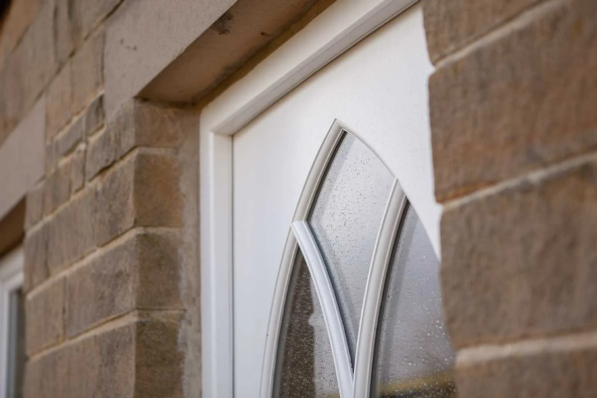 Close-up of a rain-covered window with a decorative frame on a brick building.