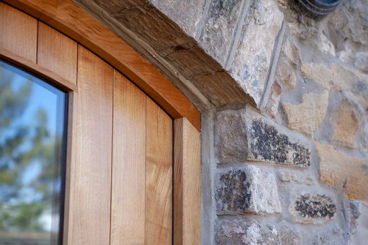 Close-up of a door frame with a wooden interior and a stone exterior wall.