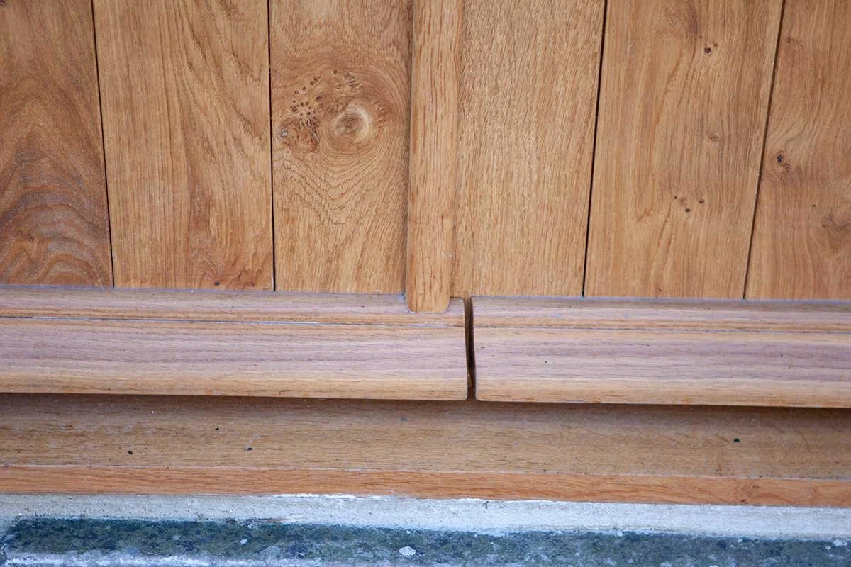 Close up of a wooden door with a small gap at the bottom.