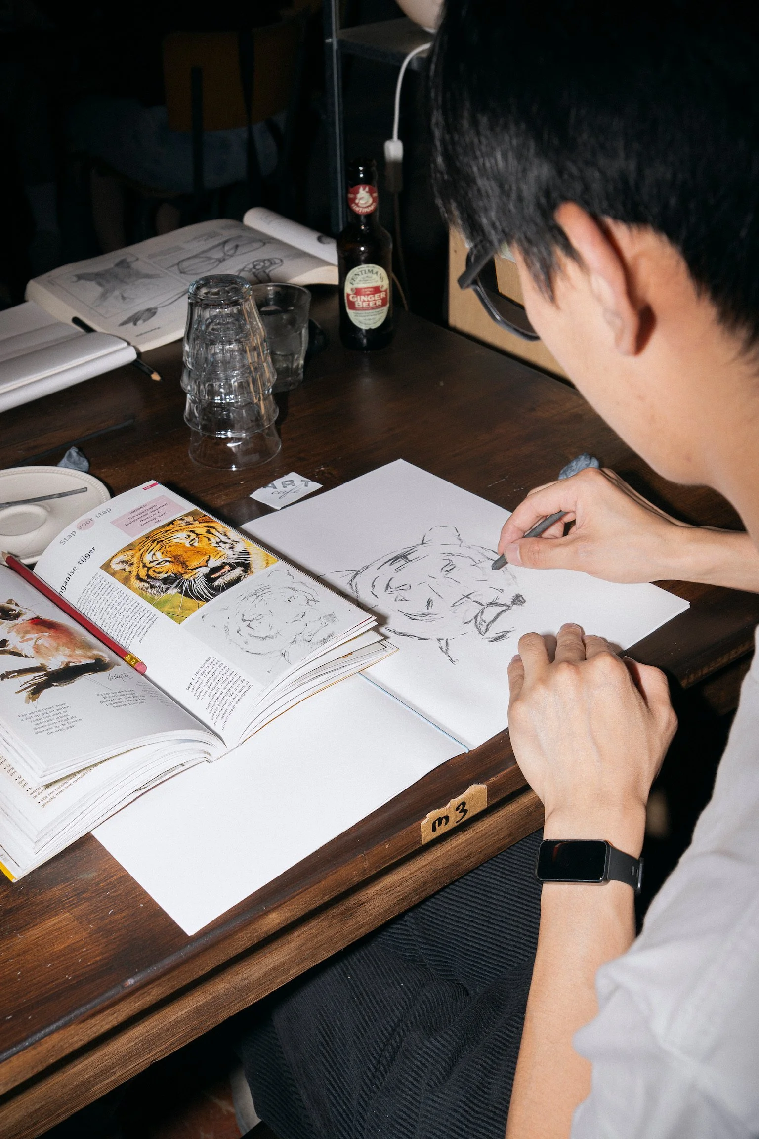 Person sketching a tiger during a creative drawing workshop at The Art Café in Amsterdam city centre, a unique activity for team outings and groups.