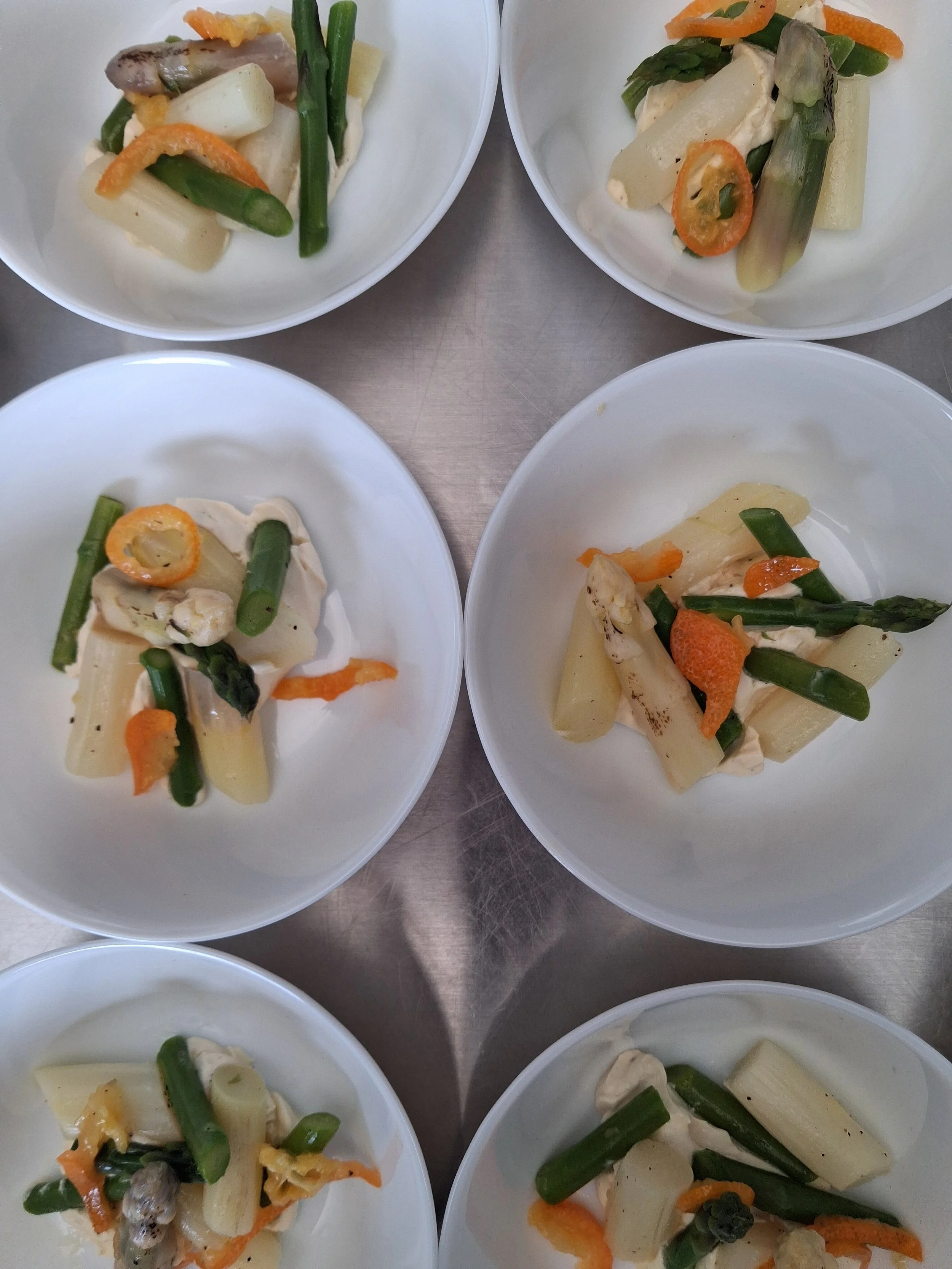 Assiettes de légumes cuits comprenant asperges vertes, carottes, céleri, pommes de terre, et champignons.