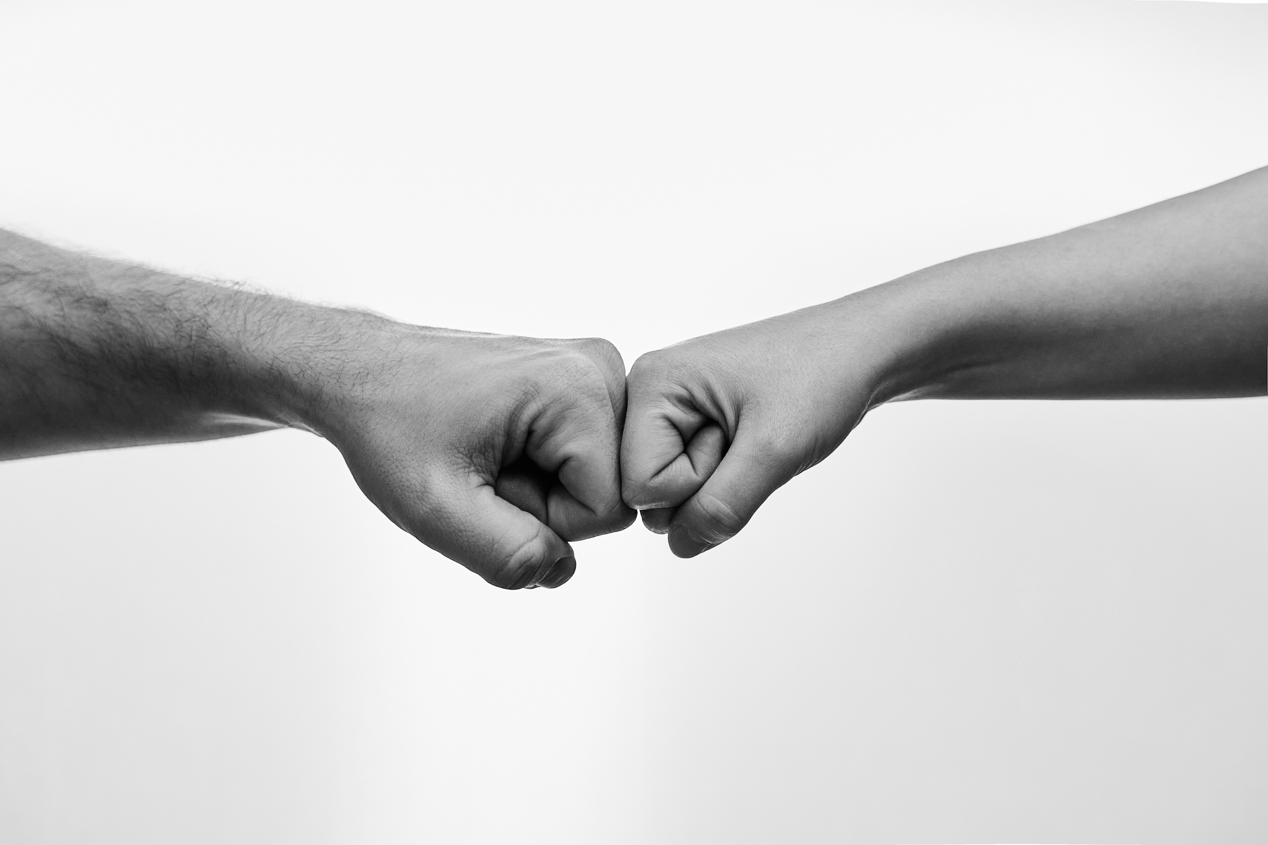 Black and white photo of two fists bumping each other in a friendly gesture.