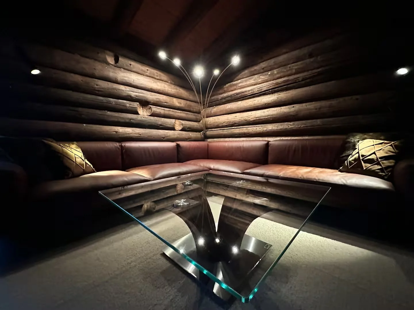 Exclusive Cigar Lounge in WEF Chalet: L-Shaped Brown Leather Sofa, Glass Coffee Table, Wood-Paneled Walls. Premium Davos Retreat for World Leaders with Private Humidor & Concierge Service. World Economic Forum, Switzerland.