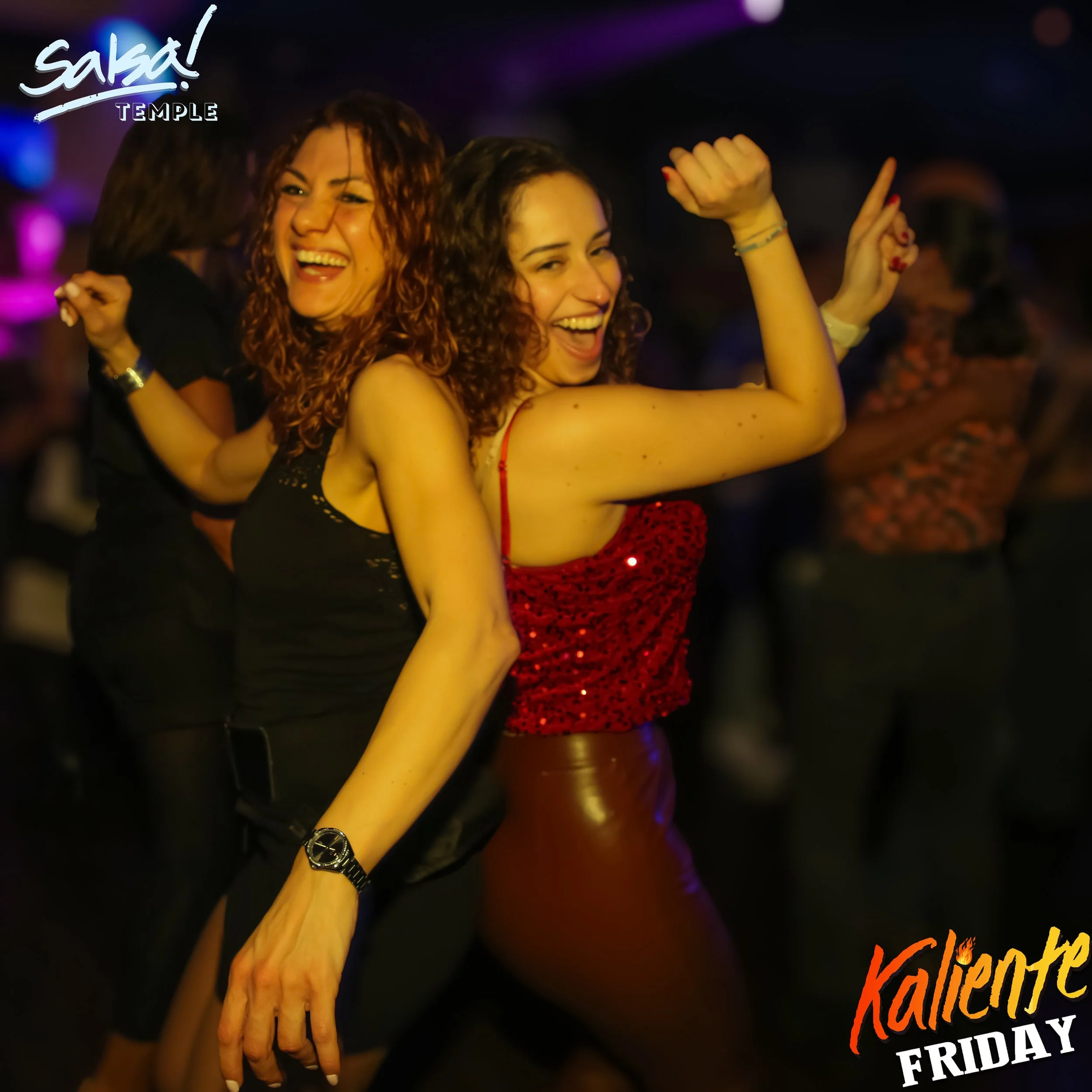 Two women dancing and smiling in a nightclub with colorful lights, wearing fashionable outfits, and having fun at an event called 'Kalinete Friday.'