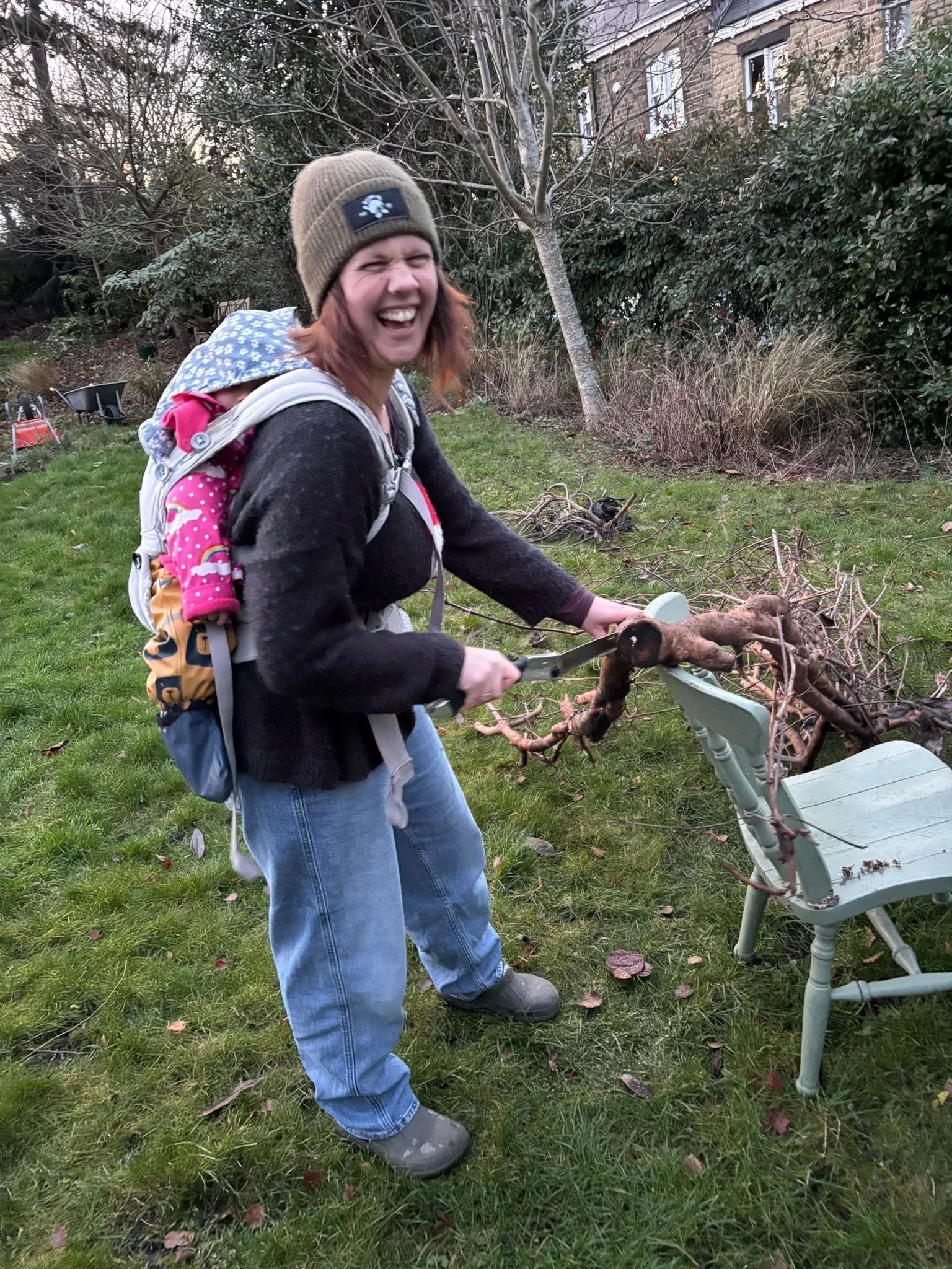 Image of Abigail Glasson doing some forestry work with her daughter on her back