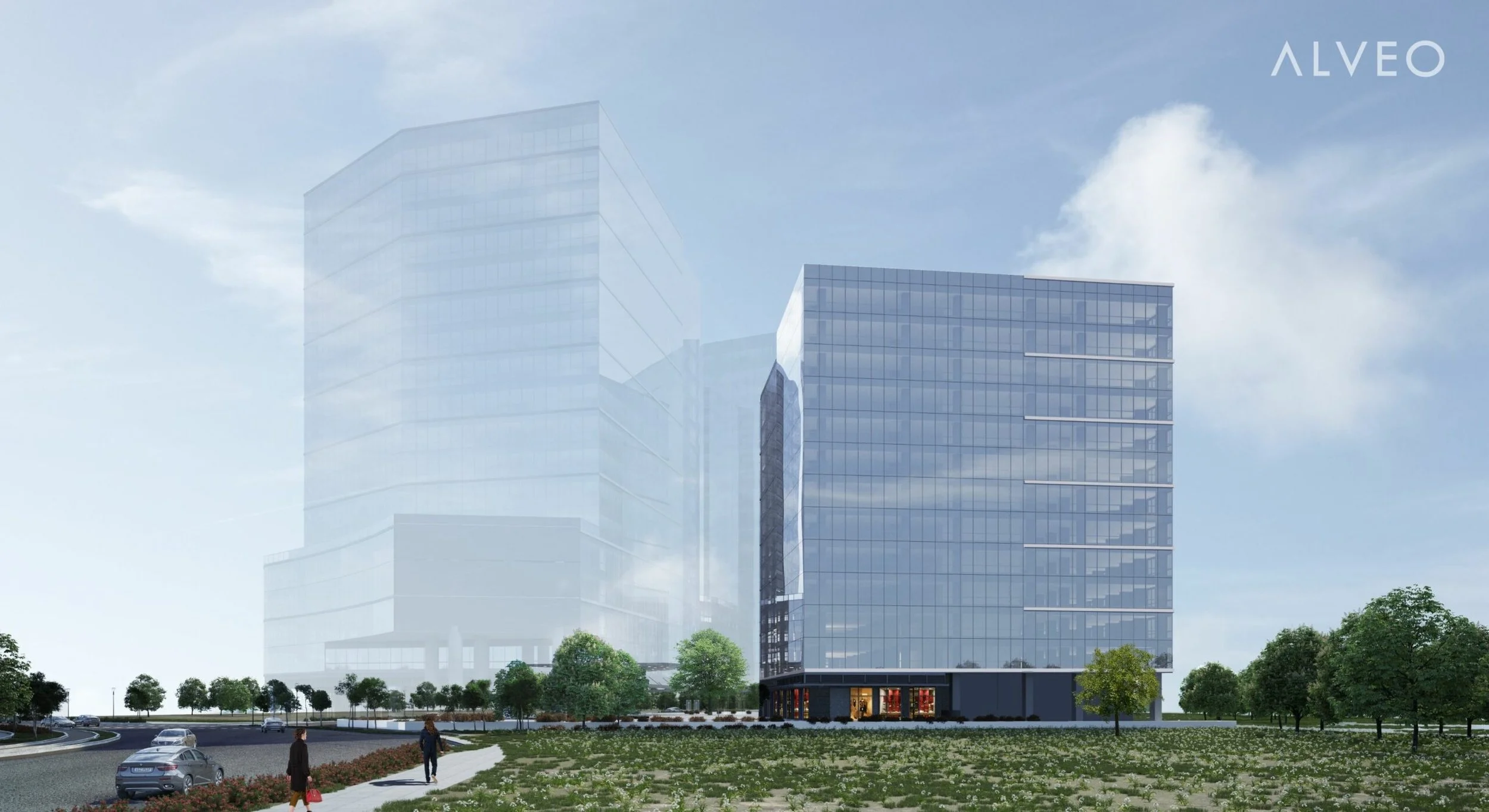 A modern, glass-fronted office building with a landscaped area in front, trees surrounding, and a parking lot with cars. The sky is partly cloudy.