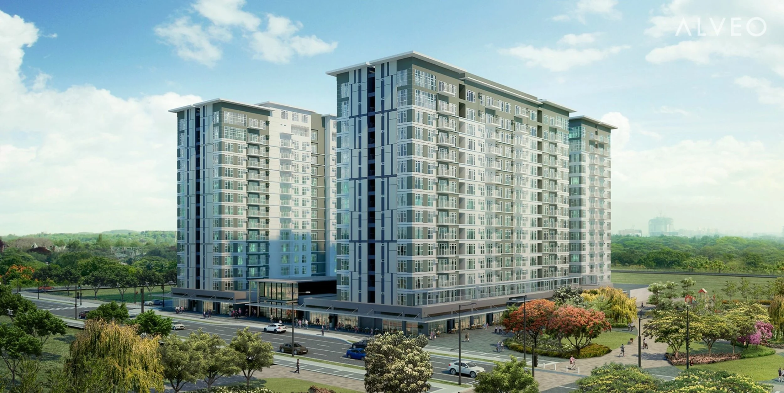 A modern multi-story residential building complex with balconies, surrounded by green trees, a road with cars, and a park area with walking paths and colorful trees.