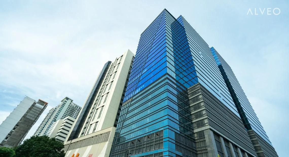 Tall modern skyscraper with reflective blue glass windows in an urban cityscape.