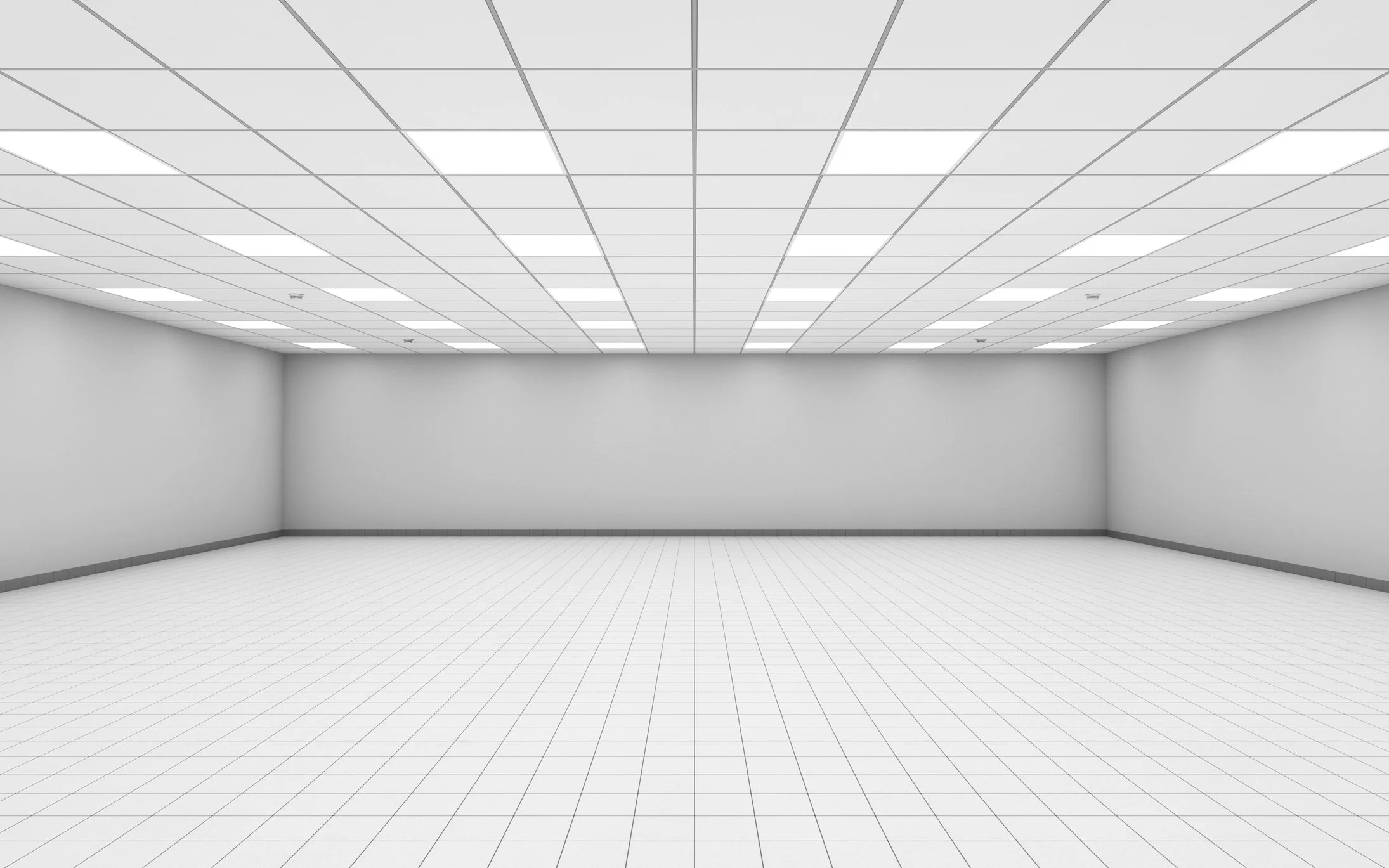 An empty, white, tiled room with a drop ceiling and gray baseboards.