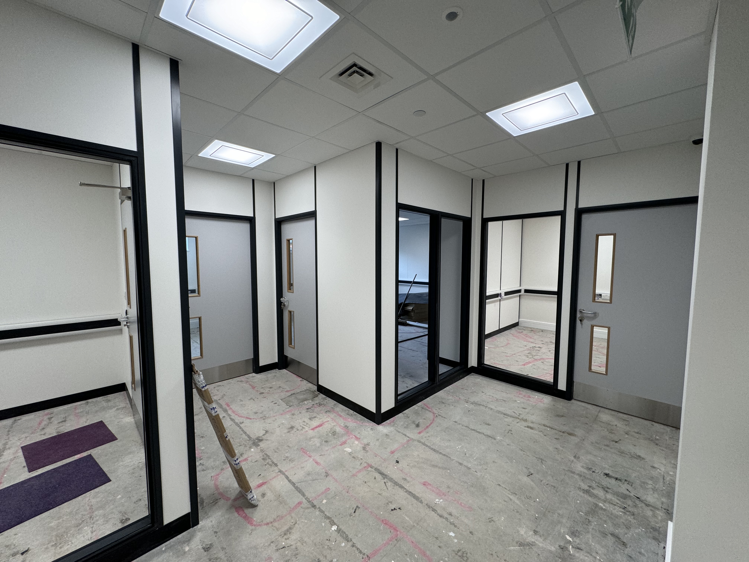 Fire-rated partition system combining solid and glazed sections, designed to meet regulations while maintaining visibility and light