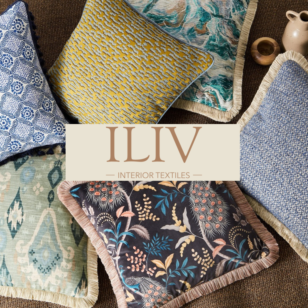 A collection of colorful throw pillows and fabric swatches with various patterns and textures, arranged on a dark surface with a beige banner in the center reading 'ILIV Interior Textiles'.