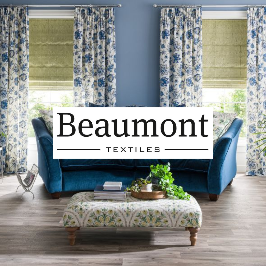 Living room with blue walls, floral curtains, green blinds, light-colored flooring, teal velvet sofa, patterned ottoman, and a tray with plants and books.