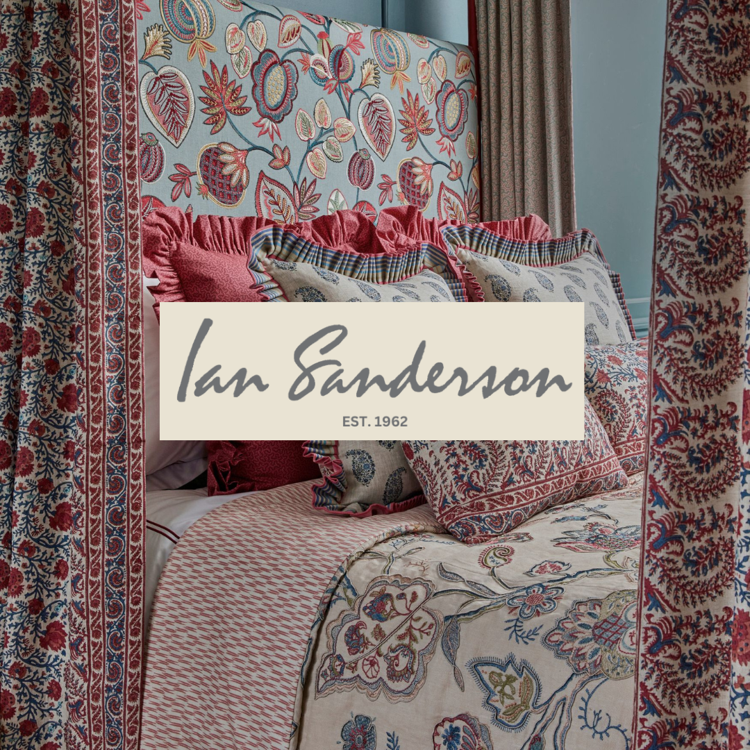 A bed with a patterned quilt, multiple decorative pillows, and a floral and leaf embroidered headboard. Surrounding curtains and wall panels feature intricate floral motifs in red, blue, and beige tones.