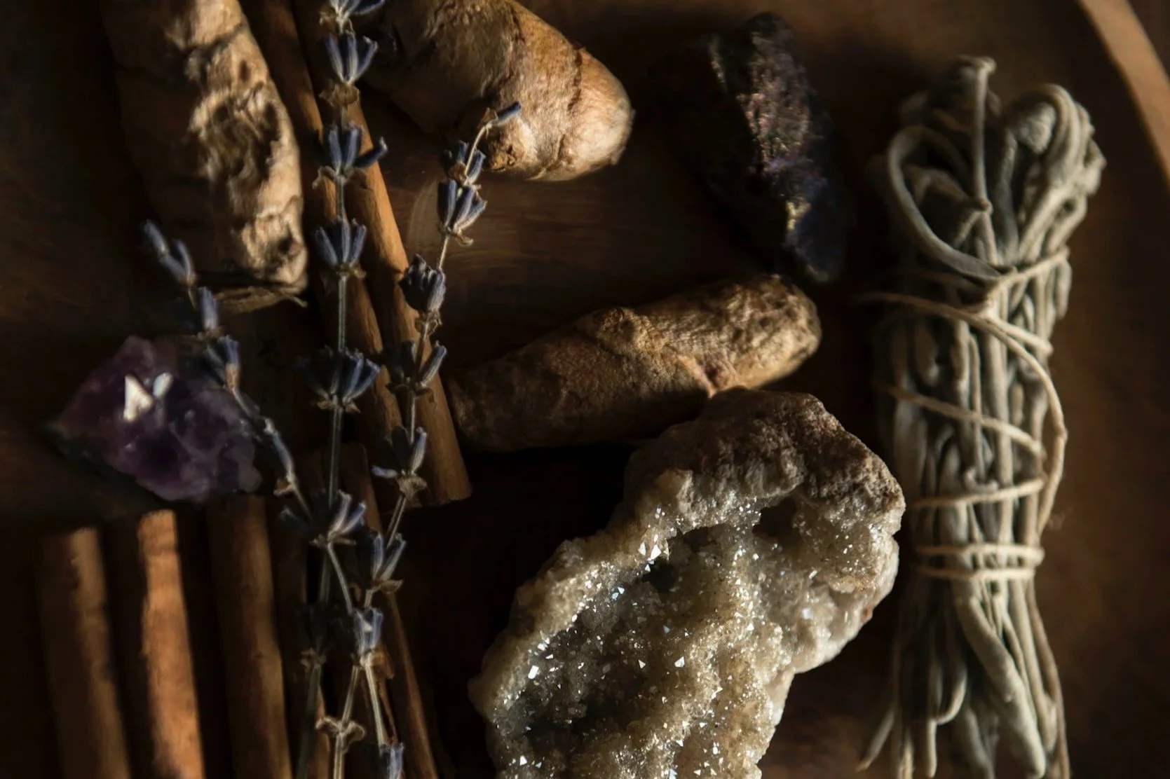 Assorted natural objects including crystals, dried flowers, stones, and a bundle of twine, arranged on a wooden surface.