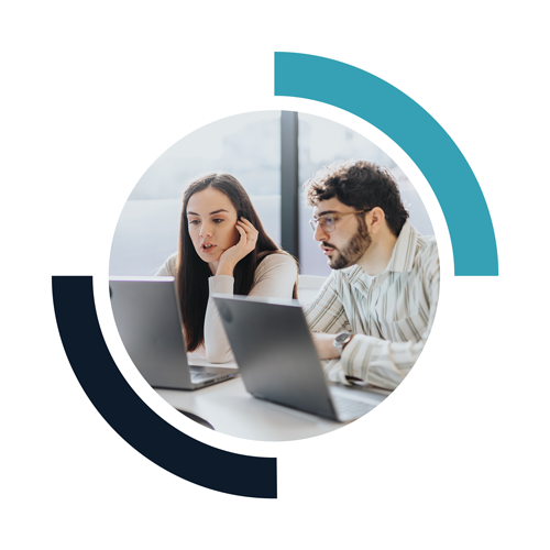 Two people working together at laptops in a modern office, engaged in a discussion.