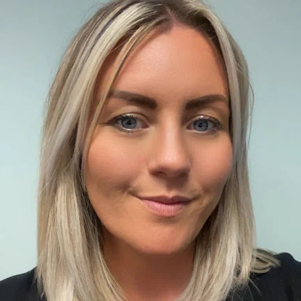 A young woman with long blonde hair, blue eyes, and light makeup smiling softly at the camera.