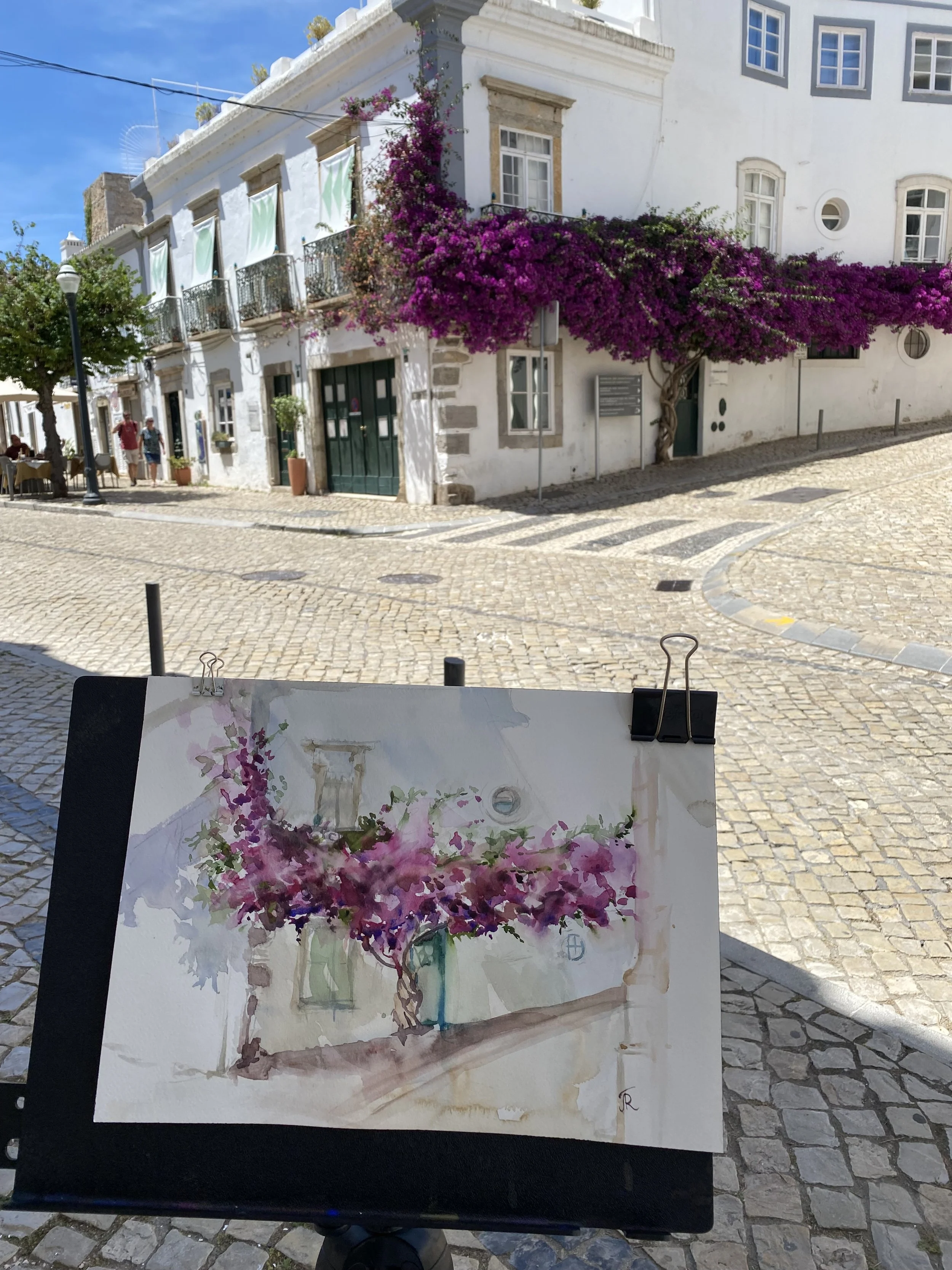 Watercolor painting of a pink and purple flowering plant in a vase, set against an interior background.