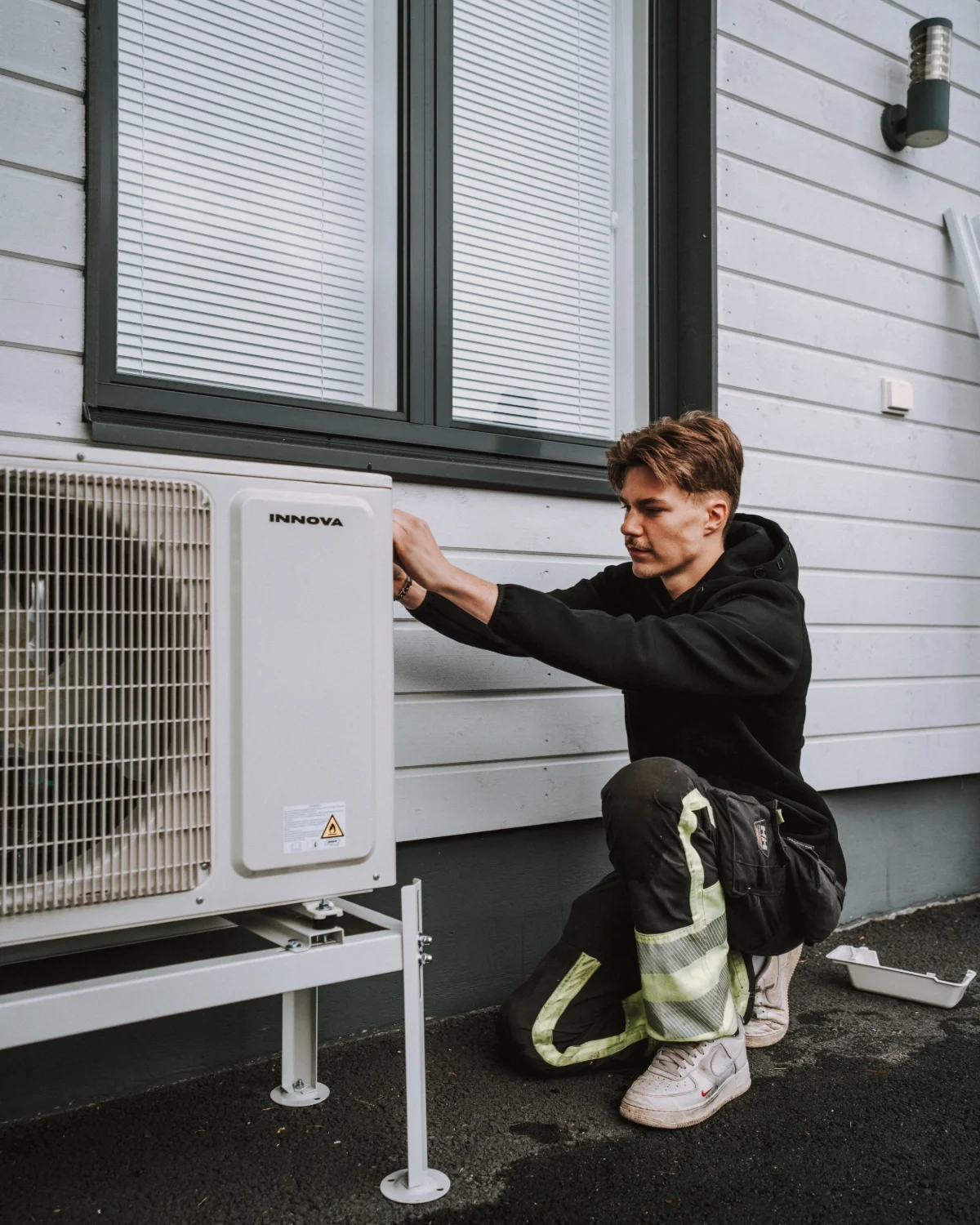 Asentaja asentamassa ilmalämpöpumppua omakotitalon seinään Pirkanmaalla