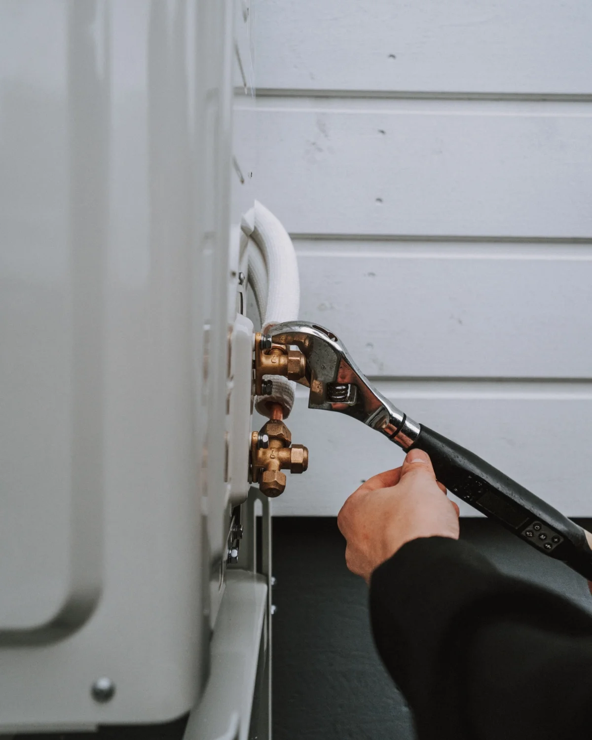 Henkilö korjaa pesukonetta käyttäen ristikulmaa vian löytämiseen.