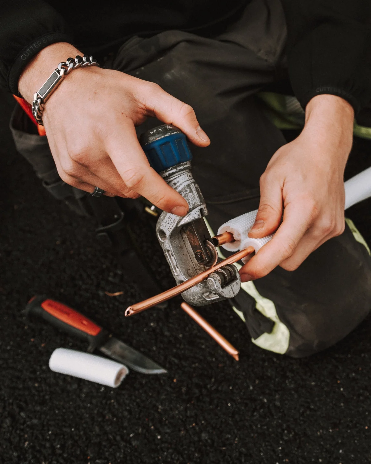 Henkilö käyttää paineilmakäsitettä työkalun ja kupariputken yhdistämiseen, puristustyökalulla.