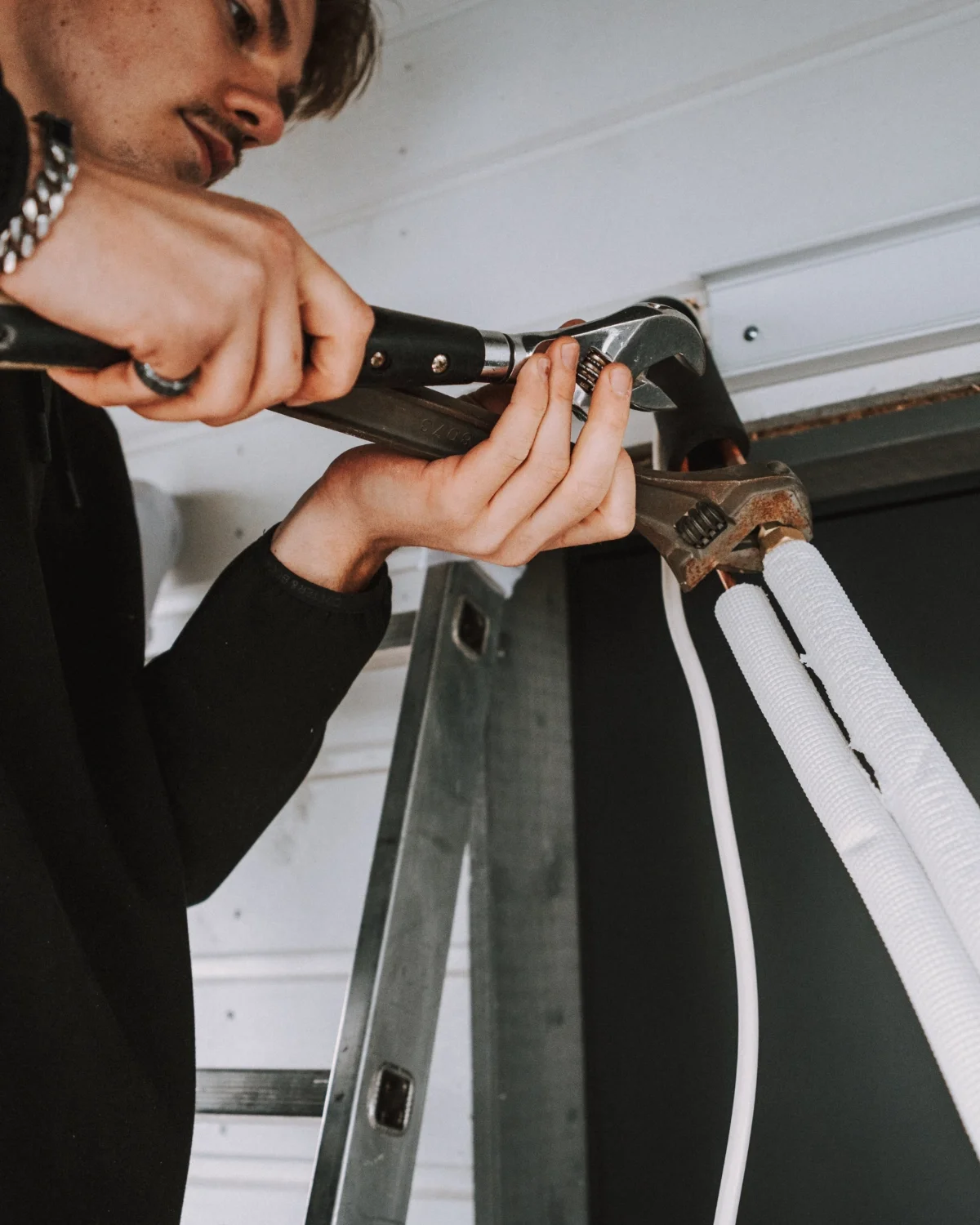 Henkilö korjaa putkiston.