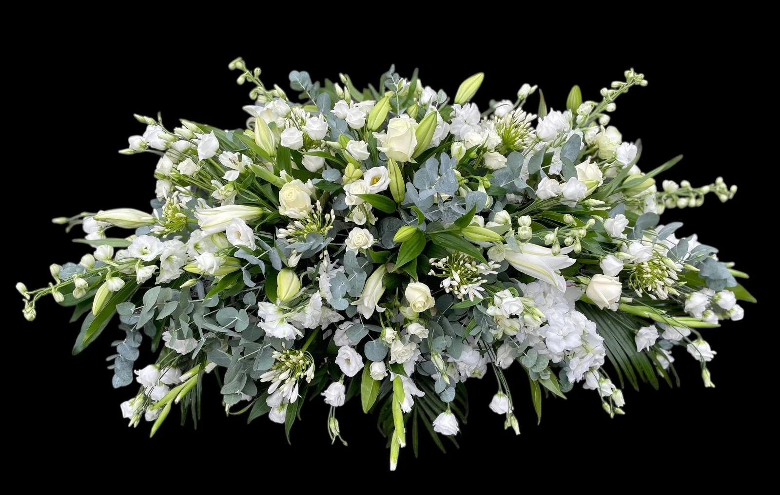 Elegant white flower arrangement with lilies and roses, accented with greenery, isolated on black background.