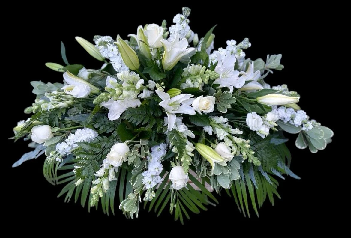 A white floral arrangement with various white flowers and green leaves against a black background.