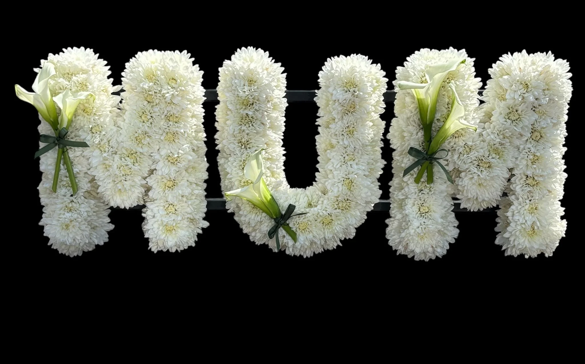 White flower arrangement spell out the word 'LOVE' against a black background.