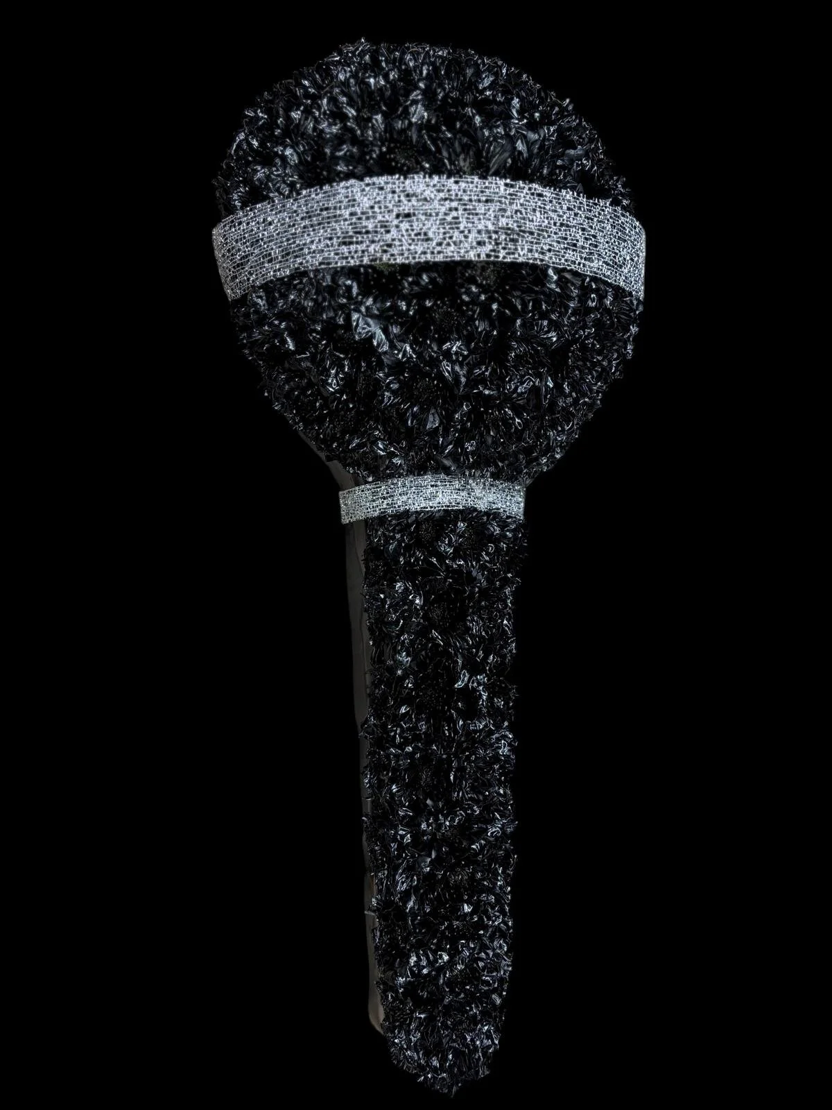 A black hairbrush with a handle, decorated with black and silver embellishments, set against a black background.