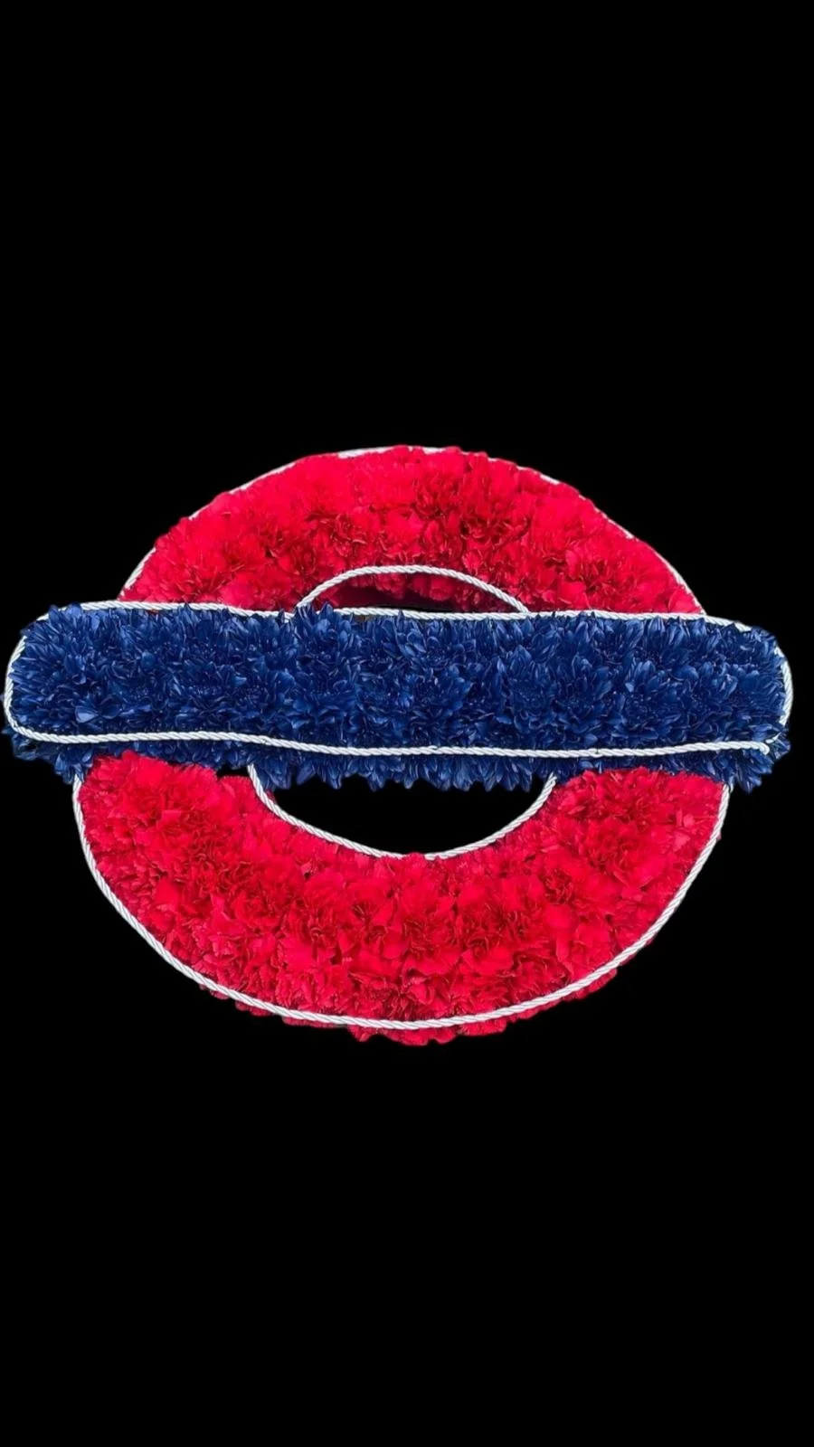 A decorative flower arrangement in the shape of a no entry traffic sign, featuring red and blue flowers on a black background.