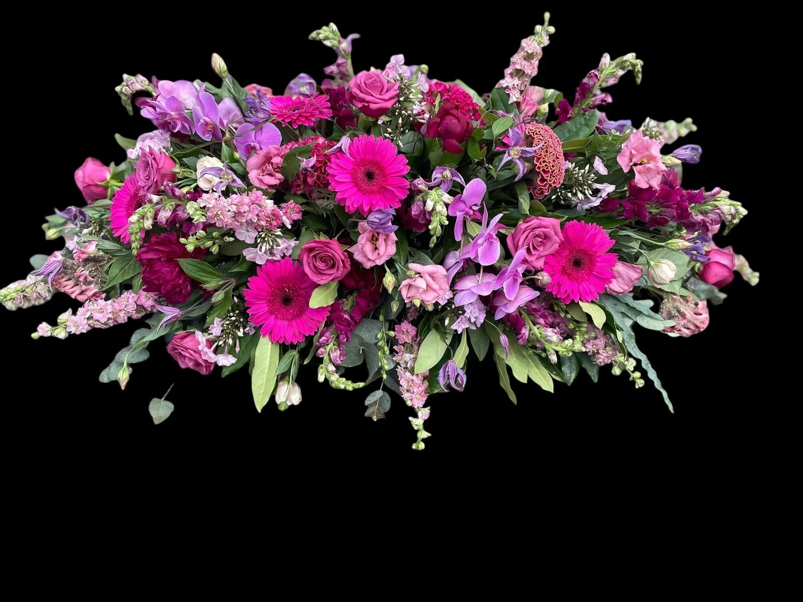 A large bouquet of pink, purple, and magenta flowers against a black background.
