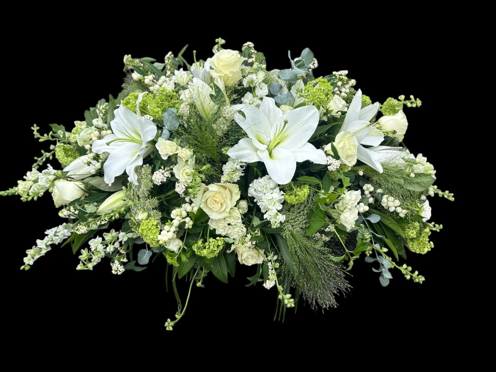 A bouquet of white flowers including lilies, roses, and hydrangeas against a black background.
