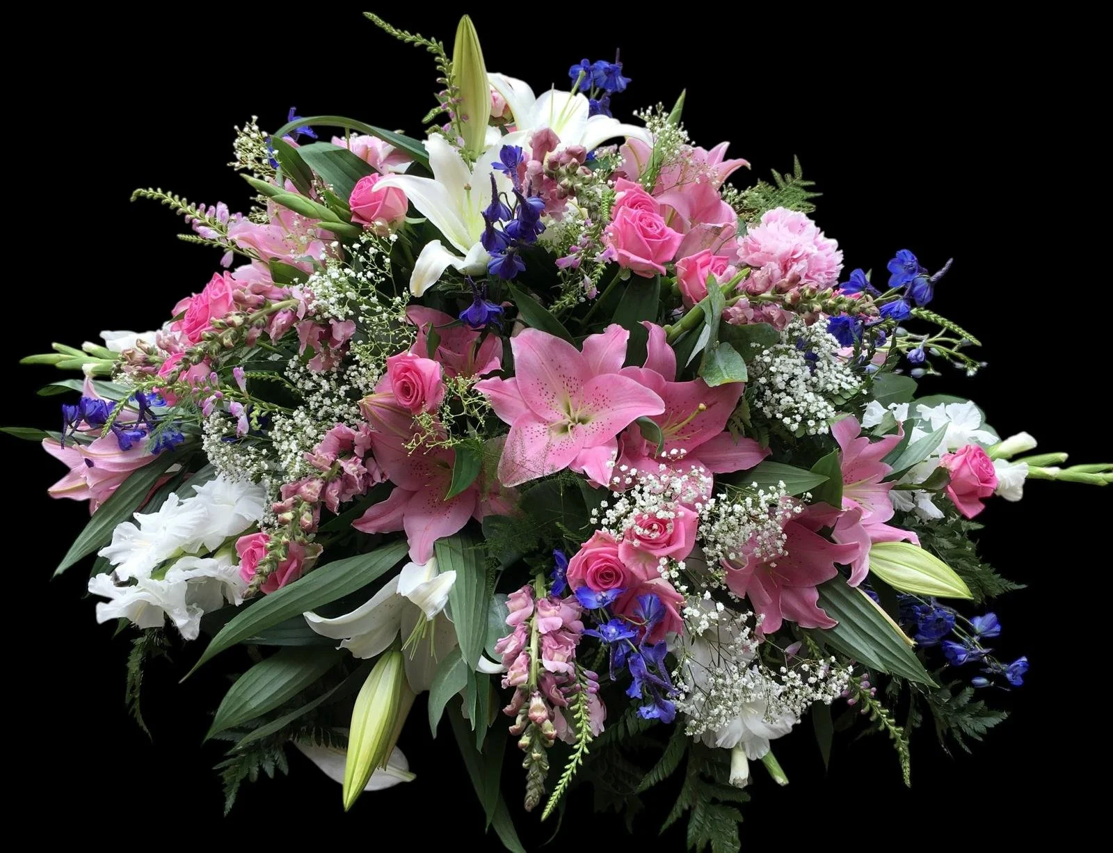 A bouquet of pink, white, purple, and blue flowers including lilies, roses, and baby's breath on a black background.