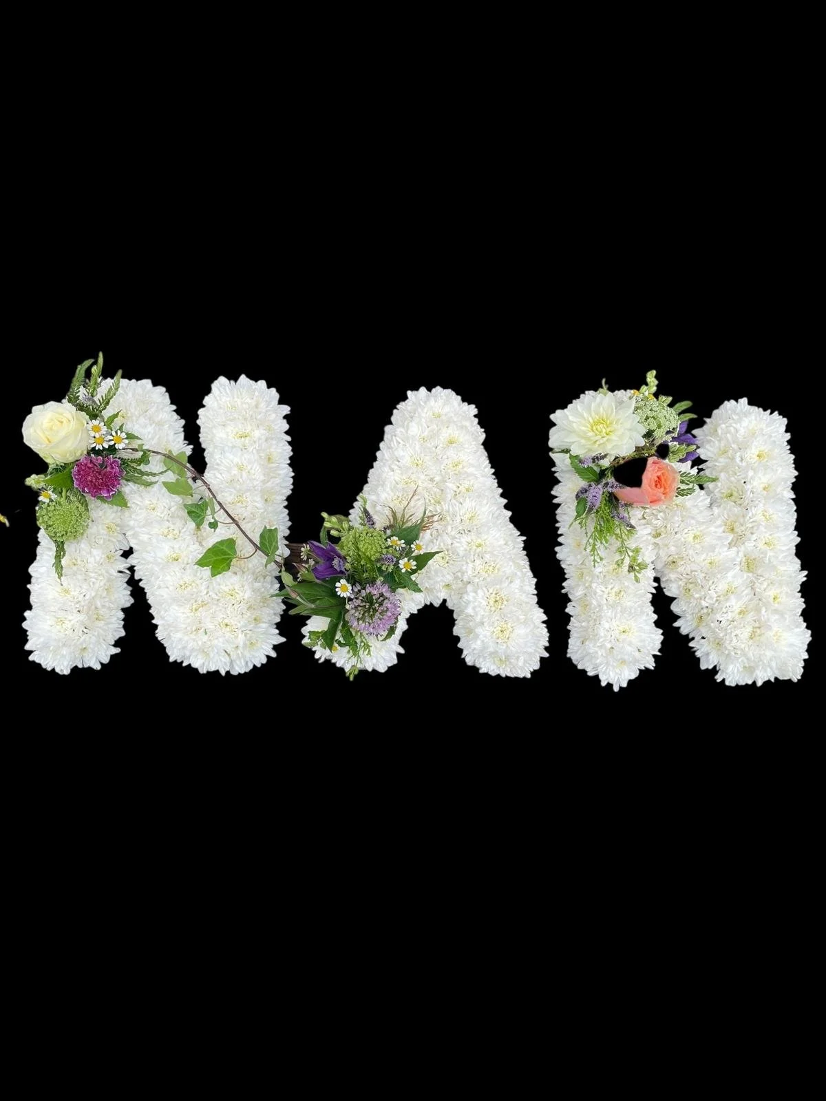 The word 'Wain' formed with white flower arrangements decorated with small colorful flowers and greenery.