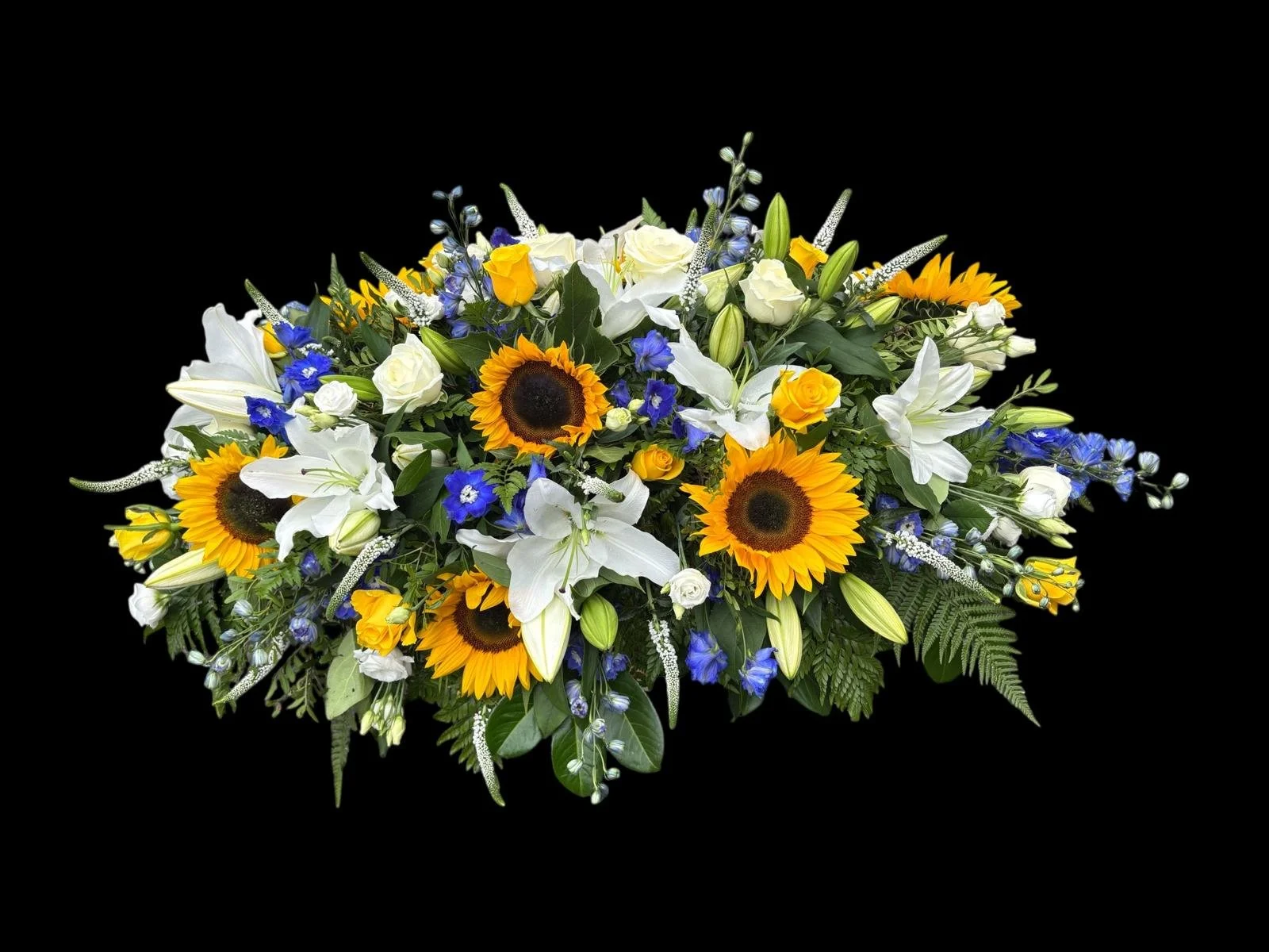 A vibrant floral arrangement featuring sunflowers, white lilies, white roses, blue delphiniums, and various greenery against a black background.