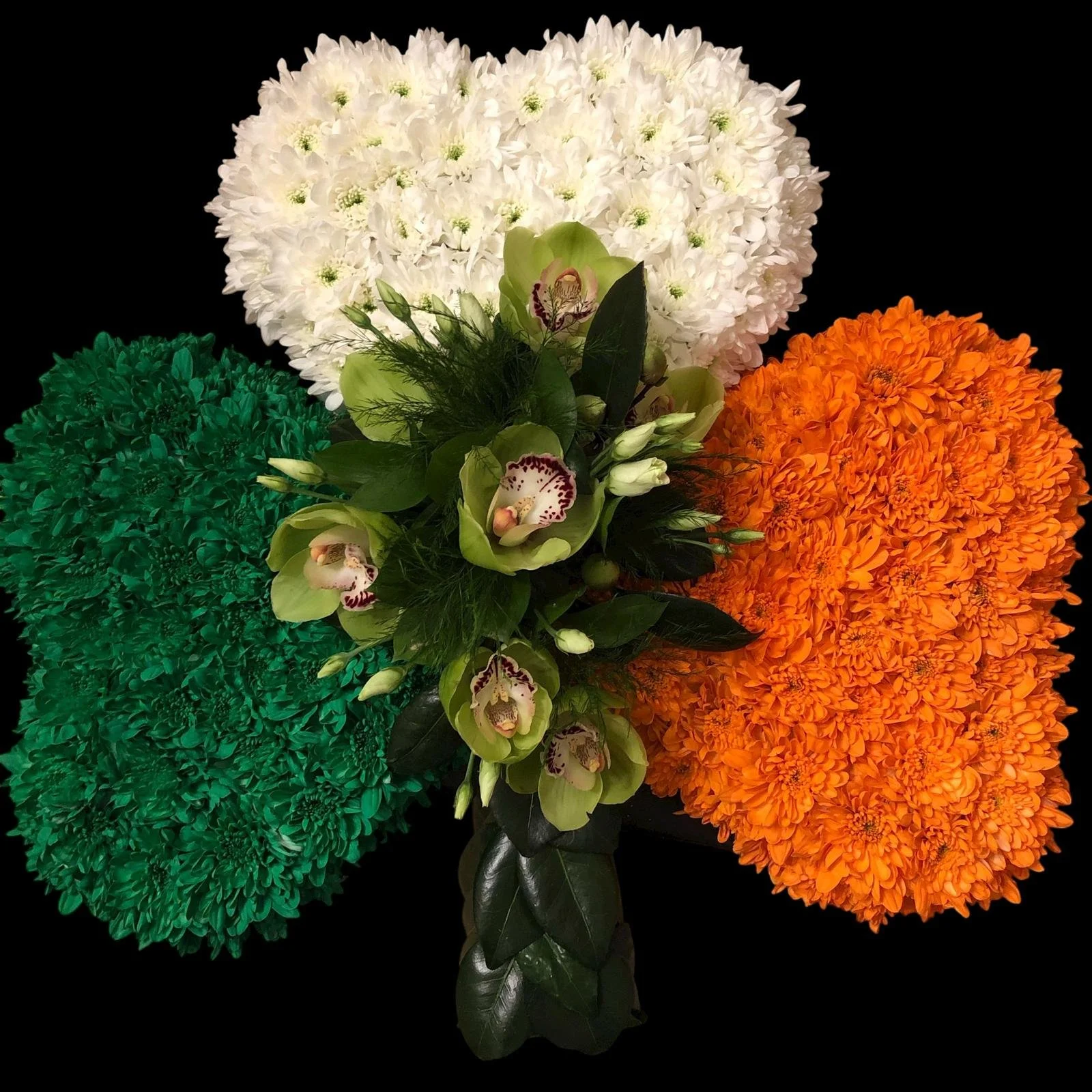 A bouquet of white, green, and orange flowers against a black background.