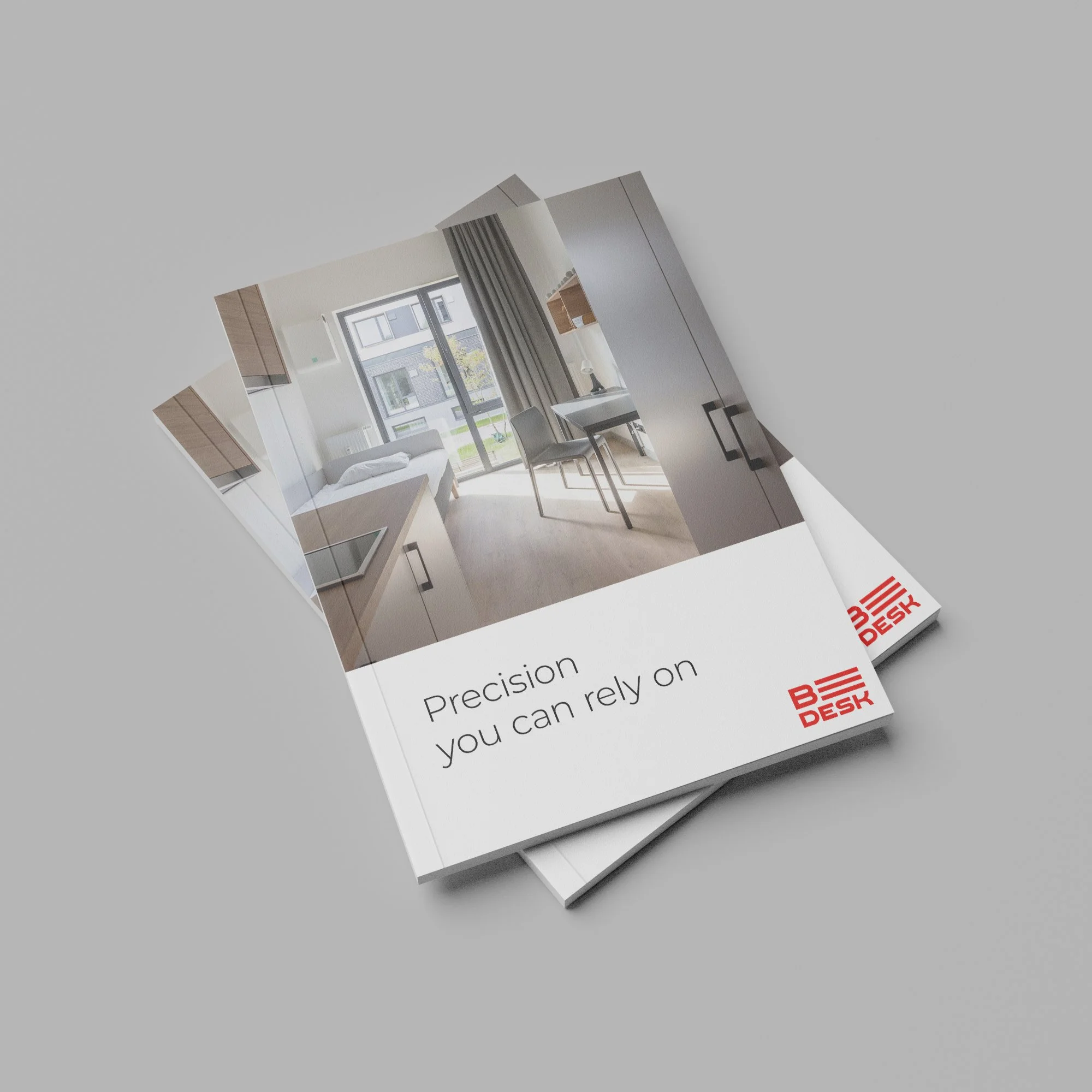Brochure with a modern studio apartment image and the text 'Precision you can rely on' and 'B DESK' logo.