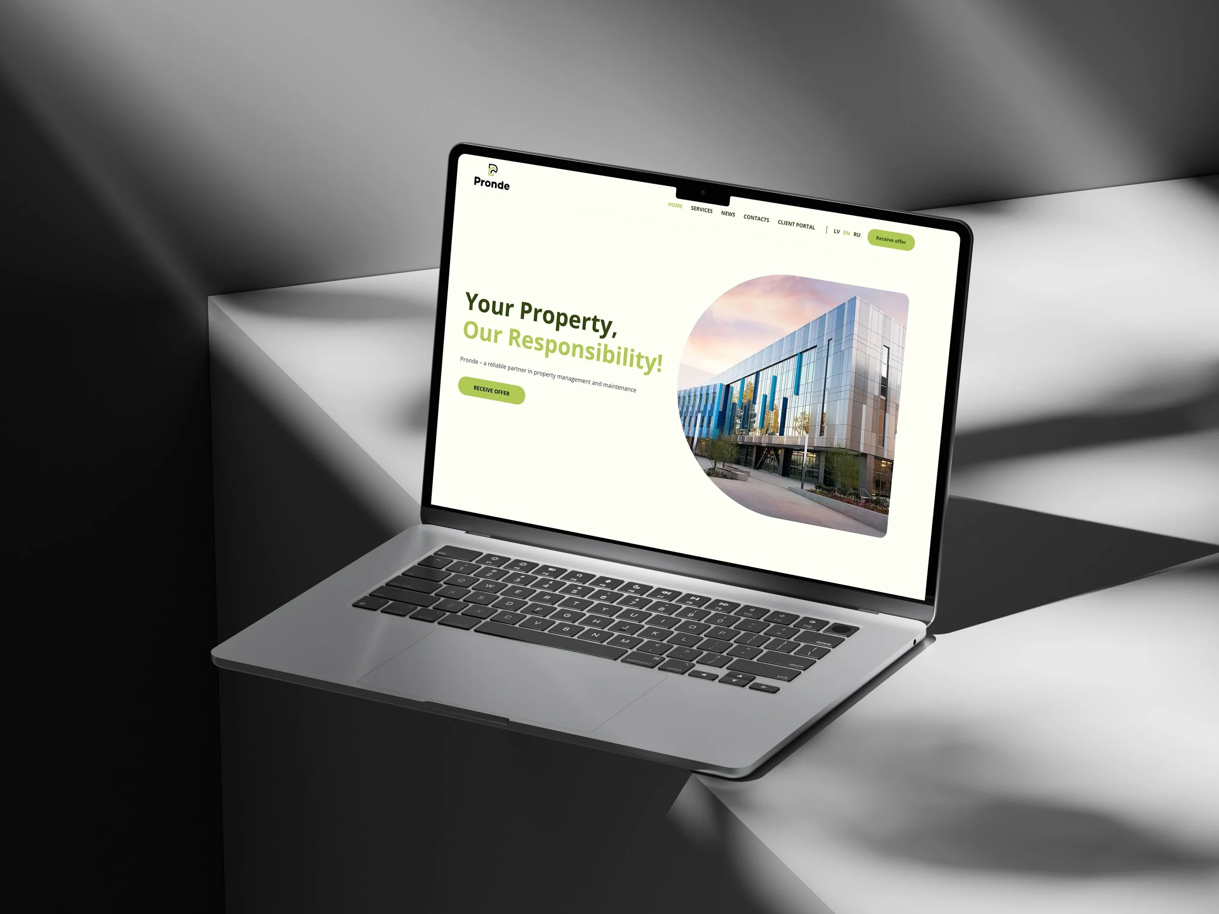 Laptop on a white surface displaying a property management website with an image of a modern building.